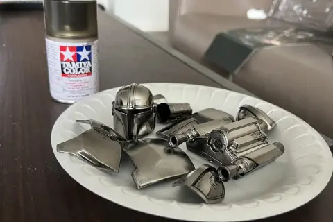 Vernice cromata spray Tamiya per plastica funziona. Pezzi di un elmo e armatura di un personaggio, come il Mandaloriano, pronti per essere assemblati.