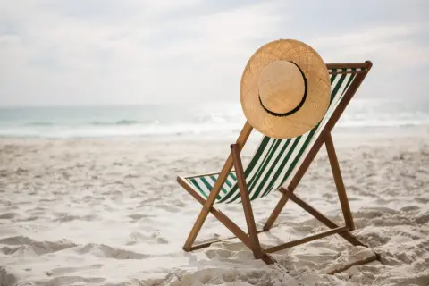 Pusta leżanka z kapeluszem na plaży, idealna na węgry wakacje. Słońce odbija się w wodzie, zapraszając do relaksu.