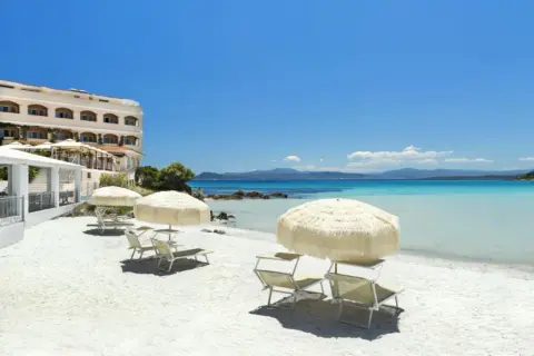 Rajska plaża na Sardynii. Biały piasek, turkusowa woda i hotel. Idealne miejsce na relaks.