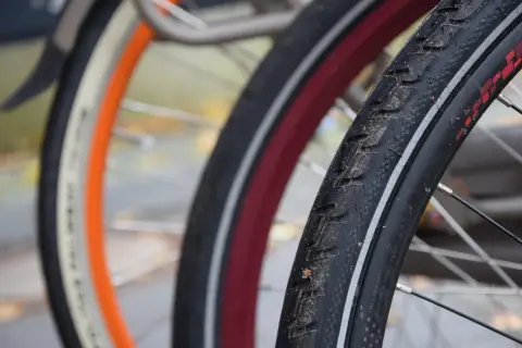 Zbliżenie na opony rowerowe 29 cali z widocznymi bieżnikami i obręczami w różnych kolorach.