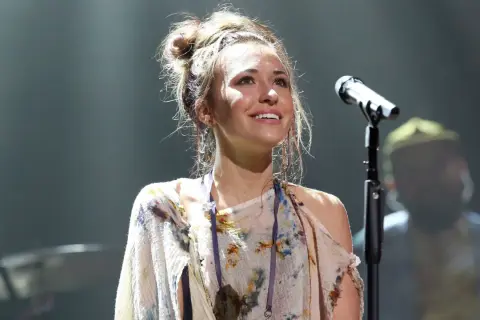 Lauren Daigle, mit hochgesteckten Haaren und einem bunten Kleid, singt auf der Bühne ins Mikrofon.