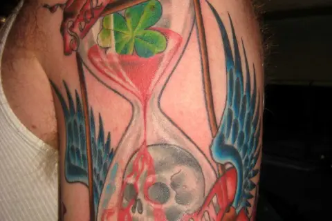 Ein **tattoo sanduhr zerbrochen**, die Zeit fließt unaufhaltsam, symbolisiert Vergänglichkeit und Neuanfang.