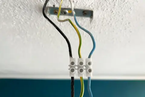 Drei Kabel (schwarz, grün-gelb, blau) sind mit einer Klemme verbunden, bereit zum Lampe abmontieren.