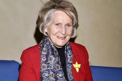 Uśmiechnięta Irena Santor w czerwonej marynarce i wzorzystym szalu. Wiele osób zastanawia się, ile lat ma Irena Santor, a jej wygląd świadczy o witalności.