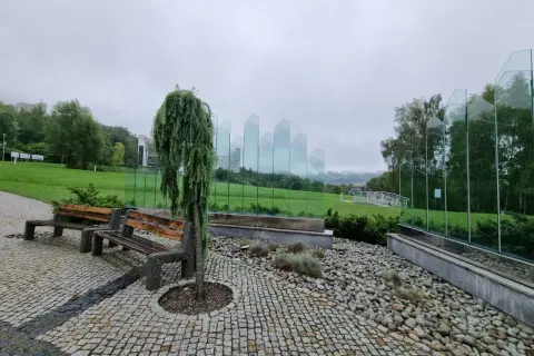 Ławki i ozdobne drzewko w Ustroniu, idealne na deszczowe atrakcje. Szklane panele tworzą nowoczesną instalację.