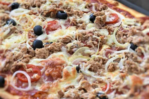 Pyszna pizza z tuńczykiem, oliwkami, cebulą i pomidorami, obficie posypana serem. Idealna na szybki obiad.