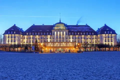 Grand Hotel w Sopocie, jeden z najpiękniejszych hoteli w Polsce, lśni nocą nad piaszczystą plażą.