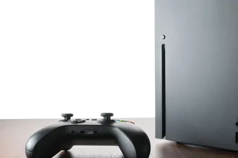 Czarny kontroler Xbox i konsola Series X na drewnianym blacie. Czy gry z Xbox 360 działają na Xbox Series X? Sprawdźmy!