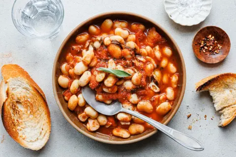 Herzhafte weiße Bohnen in Tomatensoße, garniert mit Salbei. Perfekt für einfache Salbei Rezepte, serviert mit geröstetem Brot.