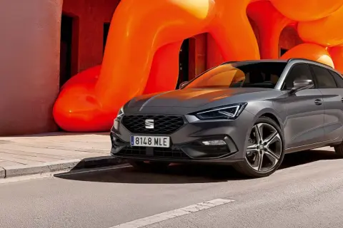 Grå Seat Leon Sportstourer parkerad framför en orange skulptur. En perfekt bil för en seat leon sportstourer test.