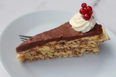En bit chokladtårta med mandelbotten, grädde och vinbär. Ett perfekt recept på daimtårta med mandelbotten.
