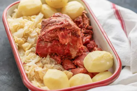 Un plato de botillo, con repollo, patatas y trozos de carne roja.