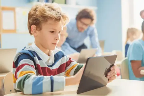 Kinder lernen mit Tablets und Laptops. Die Medien bedeutung in der Bildung ist heute enorm wichtig für die Zukunft.