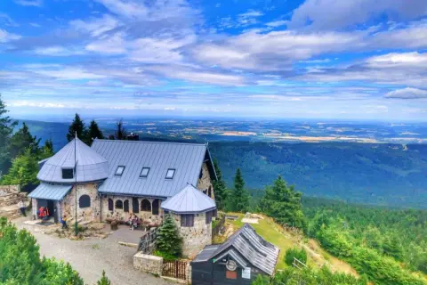 Kamienny schron turystyczny na wysokim kamieniu, skąd rozciąga się piękna trasa widokowa na doliny i pola.