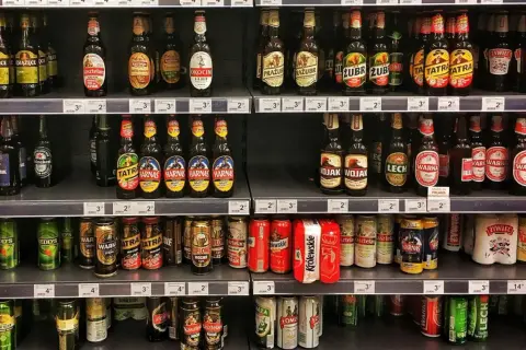 Półki sklepowe uginają się pod ciężarem piwa na półce. Butelki i puszki różnych marek tworzą kolorowy krajobraz.