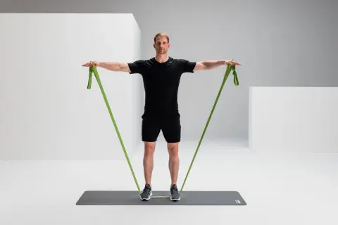 Mann trainiert mit einem grünen Widerstandsband, um seine rotatorenmanschette zu stärken.
