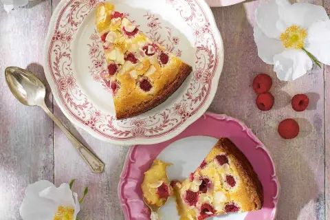En ljus kladdkaka med hallon och mandel, serverad på vackra fat. En perfekt sommardessert.