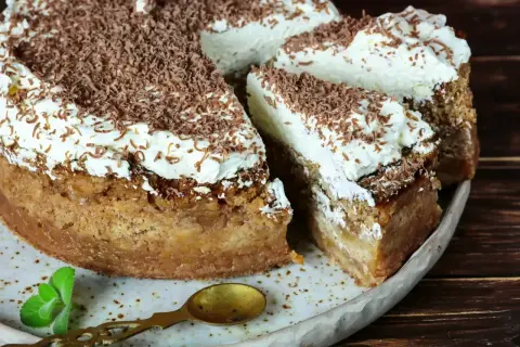 Pyszne ciasto z kremem, posypane czekoladą, z porcją bitej śmietany i listkiem mięty. Idealne na deser.