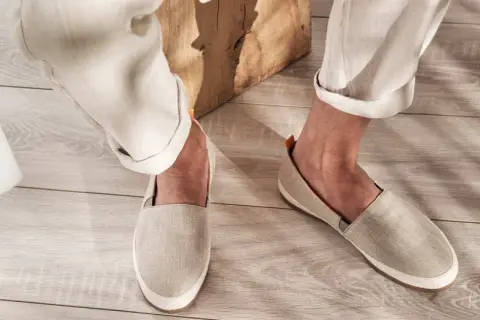Un uomo indossa un outfit casual con espadrillas uomo in lino beige, pantaloni chiari e un dettaglio in tessuto bianco.