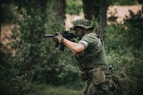 Hombre con camuflaje y pintura facial, listo para jugar airsoft que es un deporte de simulación de combate.
