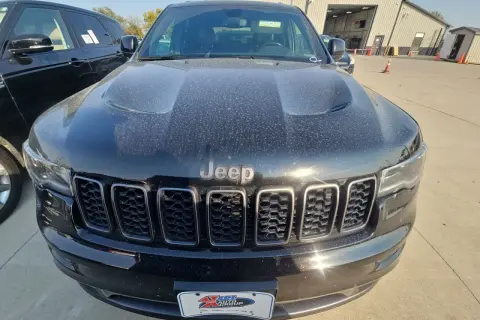Czarny Jeep Limited, pokryty kurzem, z charakterystycznym grillem i logo Jeep.