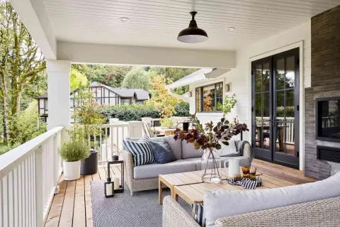 Cozy backyard makeover with a covered porch, outdoor sofa, coffee table, and fireplace.