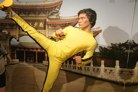 Bruce Lee w żółtym dresie wykonuje kopnięcie w powietrzu. Figura wosku w muzeum figur woskowych w Jastrzębiej Górze.