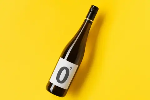 Bottiglia di vino dealcolato con etichetta "0" su sfondo giallo brillante.