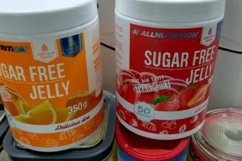 Dwie puszki galaretki bez cukru: pomarańczowa i truskawkowa. Zastanawiasz się, ile kalorii ma galaretka truskawkowa? Te produkty są niskokaloryczne.