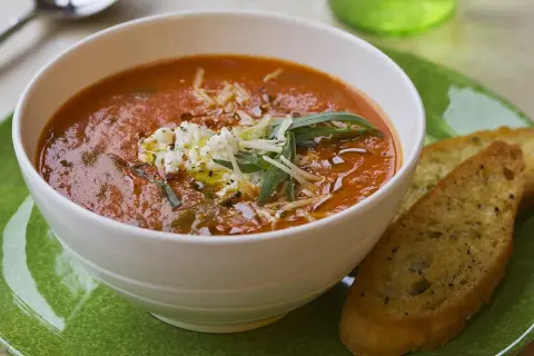 Aksamitna zupa solferino z serem feta i grzankami czosnkowymi na zielonym talerzu.