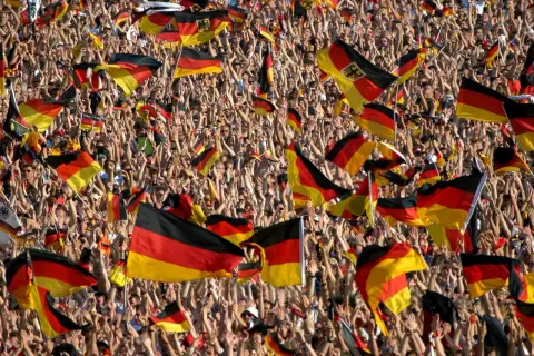 Eine jubelnde Menge mit deutschen Fahnen. Dies zeigt eine starke Form von nationalismus definition, wo die Identität durch die Nation definiert wird.