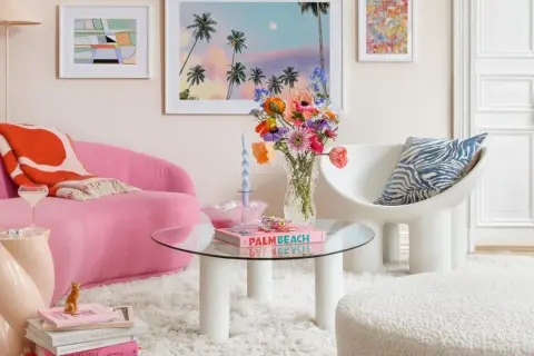 Ein Wohnzimmer im **danish pastel** Stil mit pinkem Sofa, bunten Blumen und Kunstwerken.