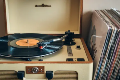 Klasyczny gramofon z płytą winylową i stosem okładek płyt. To jest właśnie to, co to jest gramofon – urządzenie do odtwarzania muzyki z płyt.