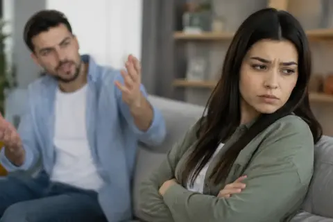 Zaborcza osoba krzyczy na partnerkę, która zamyka się w sobie, czując się przytłoczona jego kontrolą.