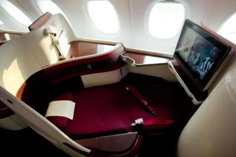 Luxuriöser Sitz im Flugzeug mit Bildschirm, der ein Fußballspiel zeigt. Hier sitzt man bequem, der beste Platz im Flugzeug für eine entspannte Reise.