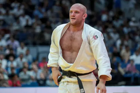 Marcus Nyman, en svensk judoka, står på mattan i sin vita dräkt med svart bälte. Publiken syns i bakgrunden.