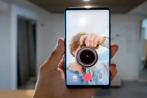 Zrzut ekranu telefonu z aplikacją do nagrywania wideo. Mężczyzna robi sobie selfie z aparatem.