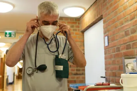 Mann mit Stethoskop und Maske im Flur, bereit für die Umschulung Gesundheits- und Krankenpfleger.