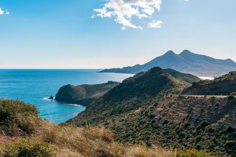 Paisaje costero en Cabo de Gata, con el mar azul intenso y montañas verdes.