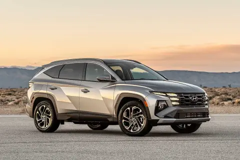 Silver Hyundai Tucson Hybrid testbil parkerad på en väg med berg i bakgrunden.