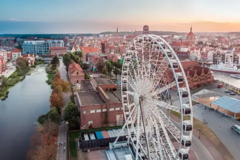 Widok na miasto z diabelskim młynem w Gdańsku. W tle rzeka Motława i zabytkowa zabudowa.