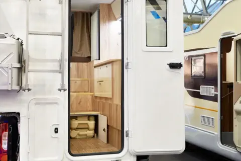 Detalle interior de autocaravana, mostrando un baño portátil y armarios de madera. Ideal para quienes buscan concesionarios de autocaravanas en Alemania.