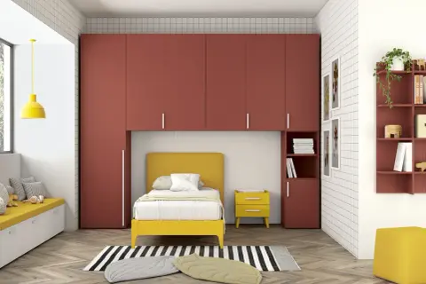 Soluzione moderna per organizzare armadio a ponte bambini: letto giallo, contenitori a muro rossi e seduta imbottita.