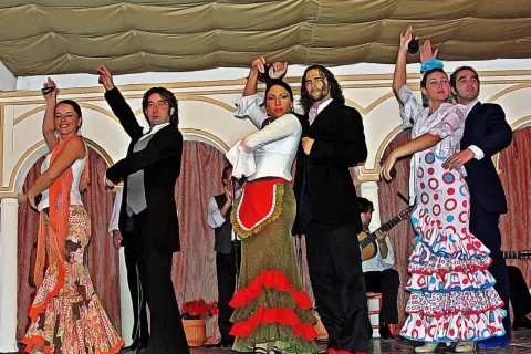 Artistas en escena, aprendiendo flamenco con pasión. Bailarines y músicos crean un espectáculo vibrante.