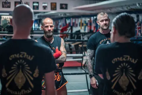 Tränare och fighters i en ring, alla bär tröjor med texten "onechai muaythai".