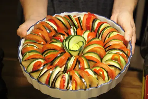 Vacker ratatouille i ugnsform, redo för ugnen. Ett perfekt ratatouille recept med skivade grönsaker som tomat, zucchini och aubergine.