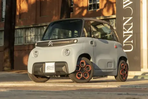 Citroën Ami, un veicolo elettrico compatto, mostra le sue prestazioni urbane con un design audace e ruote arancioni.