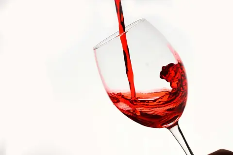 Czerwone wino, niczym reserva especial, wylewa się do kieliszka, tworząc wirujące fale.