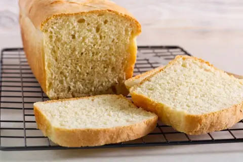 Świeżo upieczony chleb tostowy na kratce, z kilkoma kromkami obok. Idealny na śniadanie, warto sprawdzić chleb tostowy kcal.