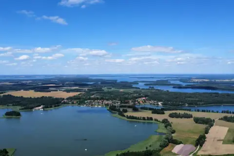 Krajobraz z lotu ptaka, gdzie widać liczne jeziora i lasy, tworzące malowniczą krainę tysiąca jezior.
